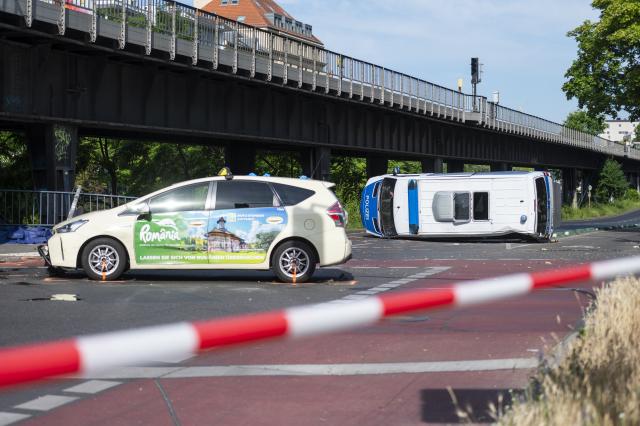 06 June 2026, Berlin: An overturned police car is lying on the road. Eight people were injured in a collision between a taxi and a police car, two of them seriously. Photo: Christophe Gateau/dpa