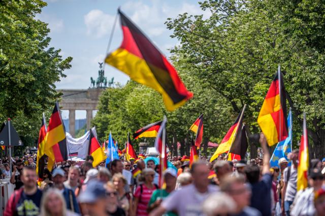 08 June 2026, Berlin: Protesters waving flags gather in front of the Brandenburg Gate during a demonstration organized by the "Project M1llion" movement, the assembly called for the immediate resignation of the current federal government and the implementation of a direct democracy modeled on the Swiss system. Photo: Michael Kappeler/dpa