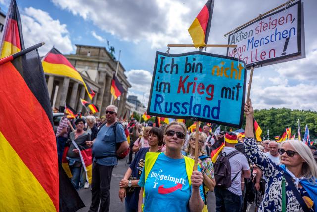 08 June 2026, Berlin: A protester holds a poster with the words "I am not at war with Russia" in front of the Brandenburg Gate during a demonstration. Organized by the "Project M1llion" movement, the assembly called for the immediate resignation of the current federal government and the implementation of a direct democracy modeled on the Swiss system. Photo: Michael Kappeler/dpa