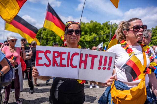 08 June 2026, Berlin: Protesters waving flags gather in front of the Brandenburg Gate during a demonstration in Berlin, Germany. Organized by the "Project M1llion" movement, the assembly called for the immediate resignation of the current federal government and the implementation of a direct democracy modeled on the Swiss system. Photo: Michael Kappeler/dpa