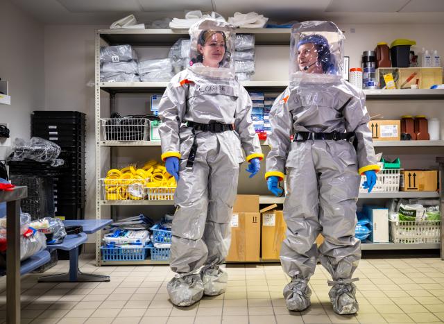 09 June 2026, Berlin: Louise Goetze (L) and Ursula Pfitzner, intensive care nurses and coordinators on the special isolation ward at Charite, put on protective suits with the help of two colleagues during a press event. Photo: Soeren Stache/dpa