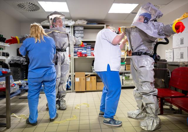 09 June 2026, Berlin: Louise Goetze (L) and Ursula Pfitzner, intensive care nurses and coordinators on the special isolation ward at Charite, put on protective suits with the help of two colleagues during a press event. Photo: Soeren Stache/dpa