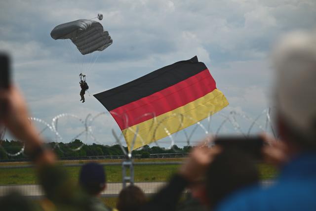 10 June 2026, Brandenburg, Schoenefeld: A Bundeswehr paratrooper carrying a German flag lands during the International Aerospace Exhibition (ILA). Photo: Sebastian Gollnow/dpa