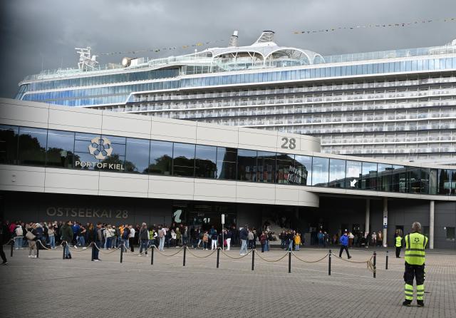 10 June 2026, Schleswig-Holstein, Kiel: Passengers wait to board a cruise ship as parts of the vessel Mein Schiff Relax and the Ostseekai terminal are evacuated on Wednesday. Photo: Katrin Luxenburger/dpa