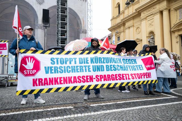 10 June 2026, Bavaria, Munich: Demonstrators hold banners during a Verdi rally on Odeonsplatz against the federal government's planned austerity measures in the public health insurance system. Photo: Lukas Barth-Tuttas/dpa