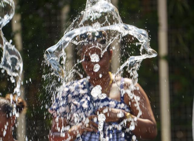 FILED - 13 August 2025, Hesse, Frankfurt/Main: FILE PHOTO - A woman stands behind a water fountain on Rathenauplatz. Photo: Andreas Arnold/dpa