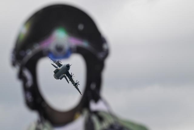 12 June 2026, Brandenburg, Schönefeld: An A400M aircraft flies past a cardboard cutout of a pilot-through which visitors can stick their heads-during the International Aerospace Exhibition (ILA) in Berlin, Germany, which runs through June 14. Photo: Sebastian Christoph Gollnow/dpa
