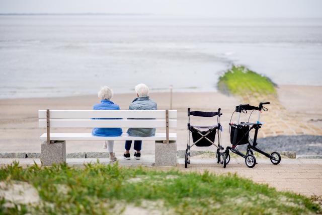 FILED - 22 May 2026, Lower Saxony, Norderney: FILE PHOTO - Two elderly women are sitting on a bench on the beach promenade on the island's west beach in sunny weather. Photo: Hauke-Christian Dittrich/dpa