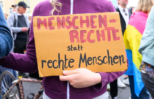13 June 2026, Brandenburg, Eberswalde: A participant in the "Many Colors - One Us" Christopher Street Day event holds up a sign. Around 1,000 people demonstrated for tolerance and diversity at the Christopher Street Day (CSD) in Eberswalde. The event, held under the slogan "Many Colors - One Us," was accompanied by a counter-demonstration by far-right extremists. According to police, both gatherings proceeded peacefully. Photo: Patrick Pleul/dpa