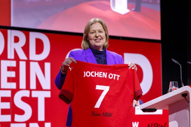 13 June 2026, North Rhine-Westphalia, Duesseldorf: Baerbel Bas, Federal Minister of Labor and Social Affairs, holds up a jersey at the SPD's state delegates' conference in North Rhine-Westphalia following the election of Jochen Ott as the party's top candidate for the 2027 state election, bearing the inscription: "Jochen Ott 7 Team NRW." Photo: Thomas Banneyer/dpa