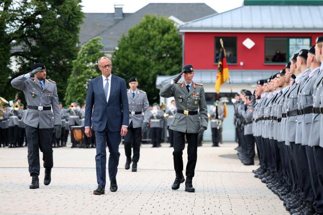 13 June 2026, North Rhine-Westphalia, Medebach: Friedrich Merz (C), Germany's Chancellor, and Christian Freuding (R), Lieutenant General and Inspector General of the Army, walk past the recruits during the Bundeswehr's ceremonial oath-taking ceremony. Recruits from the 21st Armored Brigade in Ahlen and Unna take their oath of service. Photo: Christoph Reichwein/dpa