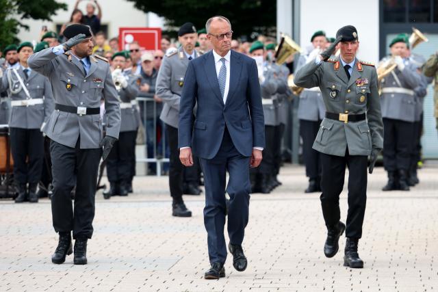 13 June 2026, North Rhine-Westphalia, Medebach: Friedrich Merz (C), Germany's Chancellor, and Christian Freuding (R), Lieutenant General and Inspector General of the Army, walk past the recruits during the Bundeswehr's ceremonial oath-taking ceremony. Recruits from the 21st Armored Brigade in Ahlen and Unna take their oath of service. Photo: Christoph Reichwein/dpa