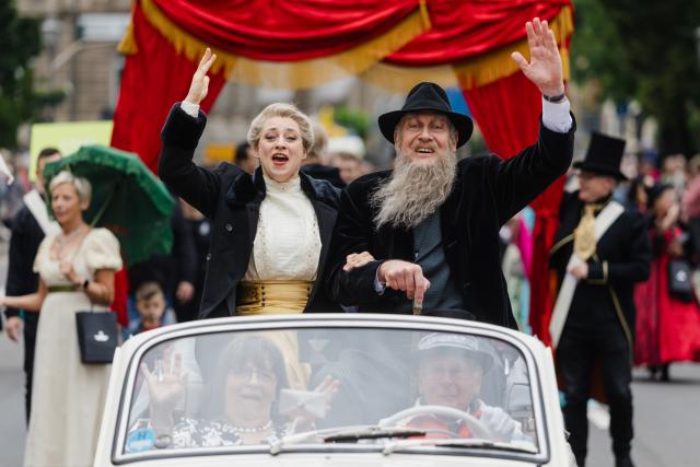 14 June 2026, Thuringia, Meiningen: Participants dressed as the "Theater Duke" and Helene, Baroness von Heldburg, wave from a vintage car during a parade celebrating the 200th birthday of Georg II, the "Theater Duke" of Saxe-Meiningen.
About 50 scenes and some 2,000 participants bring the life and work of the "Theater Duke" to life during the parade. Photo: Michael Reichel/dpa