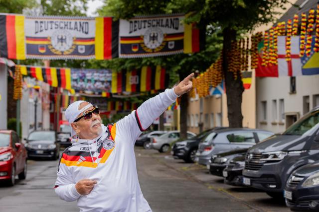 15 June 2026, North Rhine-Westphalia, Essen: The 70-years-old German football fan "Flaggen-Achim" stands amidst flags on Rullich street in Essen-Altendorf. "Flaggen-Achim" has once again transformed his street into a sea of flags for the World Cup. Photo: Rolf Vennenbernd/dpa