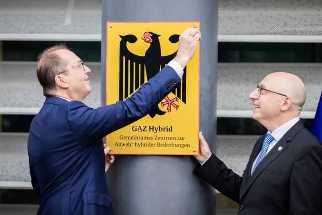 16 June 2026, Berlin: Alexander Dobrindt (L), German Minister of the Interior, symbolically attaches the plaque during the inauguration of the Joint Center for Countering Hybrid Threats (GAZ Hybrid), in the presence of Sinan Selen, President of the Federal Office for the Protection of the Constitution. The new defense center will be located on the premises of the Federal Office for the Protection of the Constitution in Berlin-Treptow. Photo: Christoph Soeder/dpa