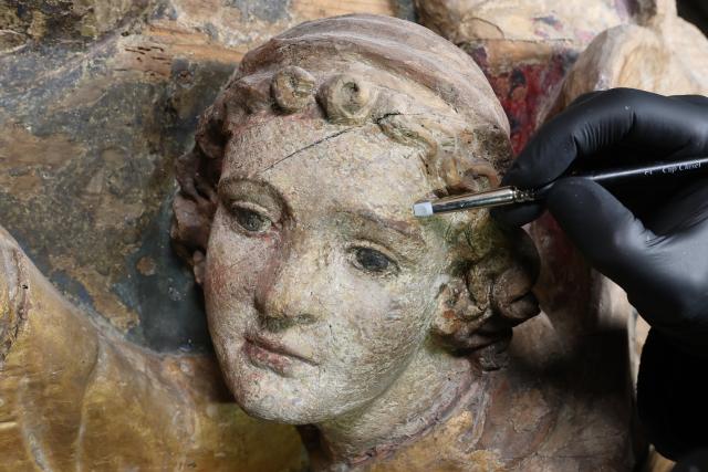16 June 2026, Saxony-Anhalt, Halberstadt: A conservator cleans an angel figure on a Romanesque crucifixion group in St. Sixtus and St. Stephen's Cathedral in Halberstadt. Cleaning and conservation work on the significant work of art will now be carried out over a two-week period. The central artwork of Halberstadt Cathedral dates back to around 1210-15 and was part of the furnishings of the Romanesque predecessor cathedral, which was consecrated in 1220. Photo: Matthias Bein/dpa