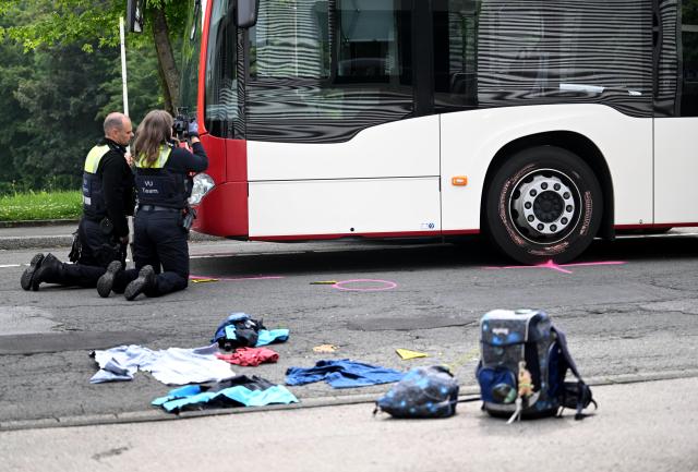 17 June 2026, North Rhine-Westphalia, Luedenscheid: Police officers work at the scene after a school bus hit a nine-year-old child. According to the initial investigation, the child reportedly ran out into the street suddenly and was struck by the bus. Photo: Bernd Thissen/dpa