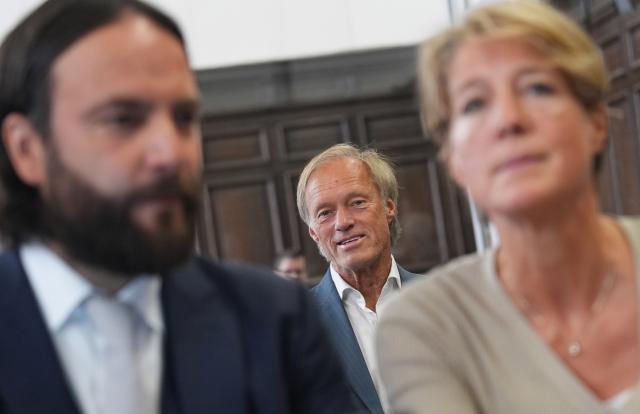 17 June 2026, Hamburg: Former television host and sports journalist Gerhard Delling (c) sits in the courtroom behind German restaurateur Christina Block (R) and her defense lawyer Ingo Bott (L) during their alleged child abduction trial. Photo: Marcus Brandt/dpa