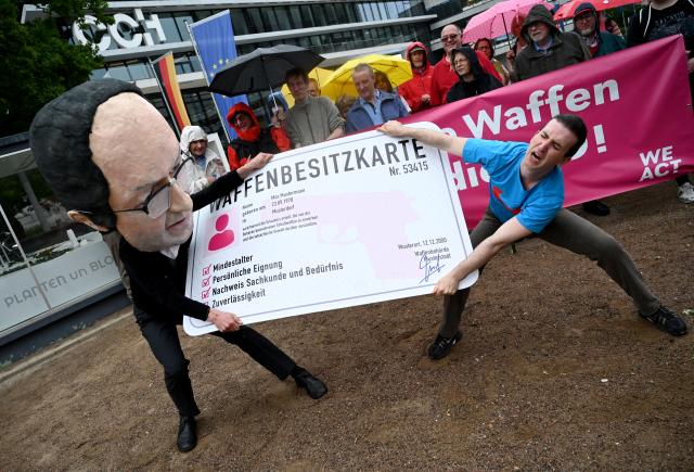 17 June 2026, Hamburg: A man dressed as Federal Interior Minister Alexander Dobrindt symbolically snatches a gun ownership permit from a man dressed as an Alternative for Germany (AfD) member during a WeAct initiative protest calling for a ban on firearms for AfD members on the sidelines of the 2026 Conference of Interior Ministers. Photo: Daniel Bockwoldt/dpa