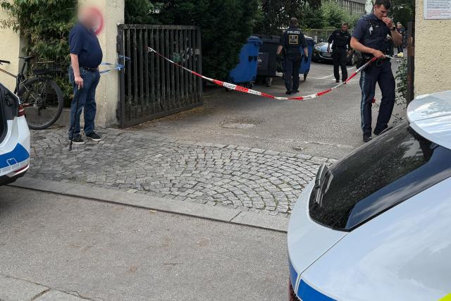 17 June 2026, Bavaria, Munich: Police officers block the entrance to a property. Dozens of patrol cars are on the scene in downtown Munich to apprehend a fugitive, who is suspected of robbing a jewelry store. Photo: Christof Rührmair/^dpa/dpa - ACHTUNG: Person(en) wurde(n) aus rechtlichen Gründen gepixelt