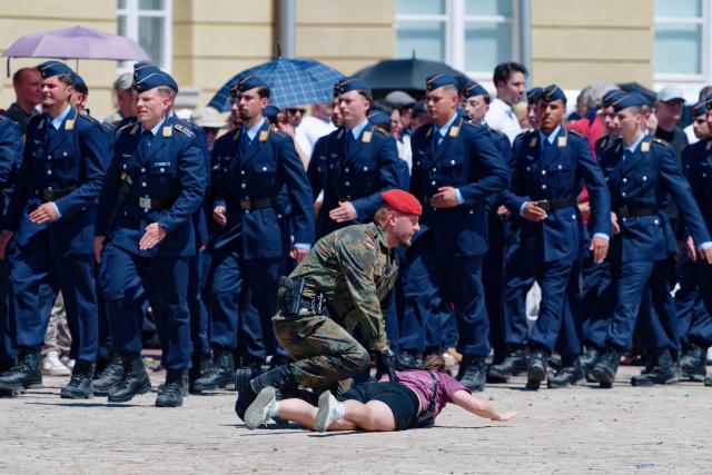 18 June 2026, Baden-Wuerttemberg, Karlsruhe: A protester is being restrained by military police as soldiers march into the Schlossplatz for the ceremonial oath-taking of more than 350 recruits. Photo: Uwe Anspach/dpa