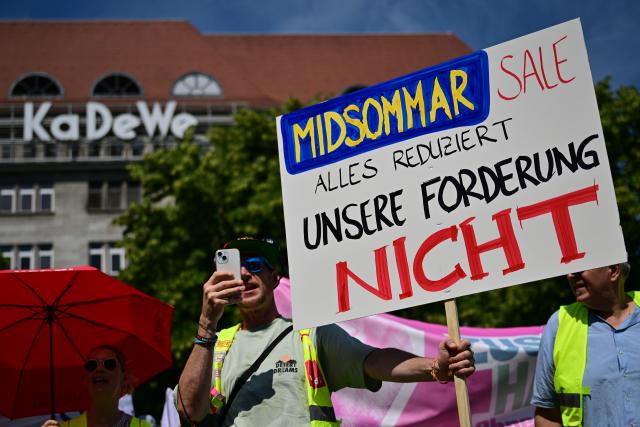 19 June 2026, Berlin: "The Midsommar sale doesn't reduce our demands" reads a poster displayed during a nationwide warning strike in the collective bargaining round of the United Services Union (ver.di). Photo: Sebastian Christoph Gollnow/dpa