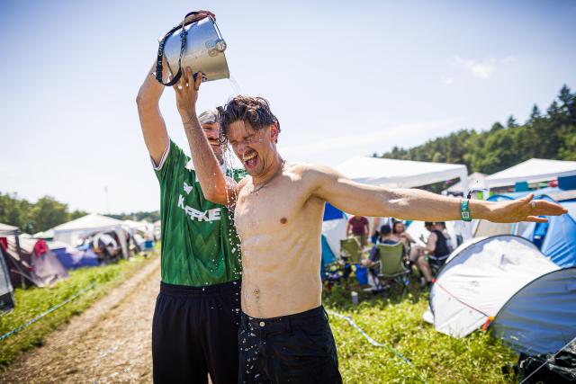 19 June 2026, Lower Saxony, Scheessel: Festivalgoers Leo (L) and Georg cool off with water at the Hurricane Festival campground amid midsummer temperatures. The Hurricane open-air festival takes place from June 19 to 21. Photo: Moritz Frankenberg/dpa