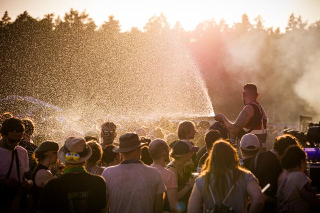 19 June 2026, Lower Saxony, Scheessel: A security guard sprays water on festivalgoers at the Hurricane Festival grounds amid sweltering summer temperatures. The Hurricane open-air festival takes place from June 19 to 21. Photo: Moritz Frankenberg/dpa