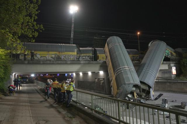 20 June 2026, Bavaria, Munich: Two freight-train cars lie on a road after falling off a bridge in Munich. Photo: Ehsan Monajati/dpa