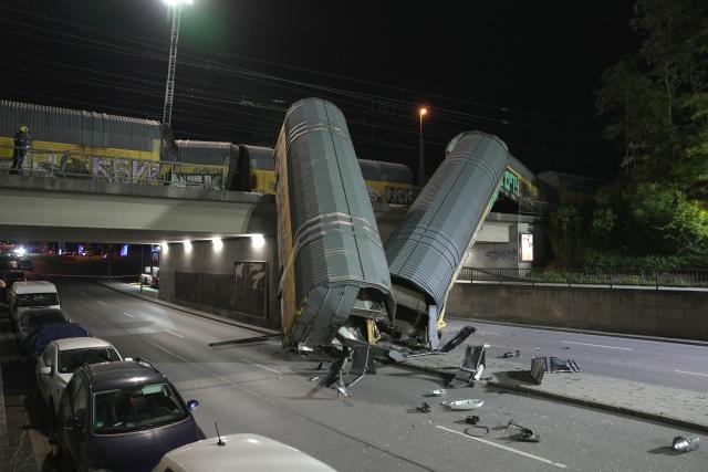 20 June 2026, Bavaria, Munich: Two freight-train cars lie on a road after falling off a bridge in Munich. Photo: Ehsan Monajati/dpa