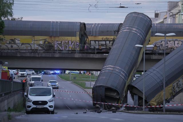 20 June 2026, Bavaria, Munich: Two freight-train cars lie on a road after falling off a bridge in Munich. Photo: Ehsan Monajati/dpa