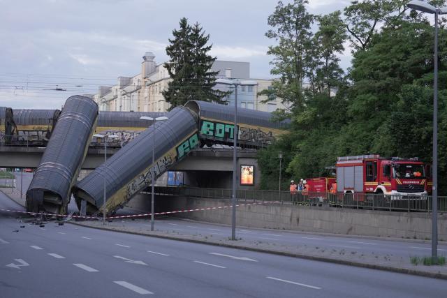 20 June 2026, Bavaria, Munich: Two freight-train cars lie on a road after falling off a bridge in Munich. Photo: Ehsan Monajati/dpa