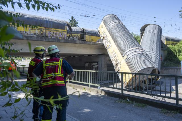 20 June 2026, Bavaria, Munich: Firefighters are examining the two cars of a freight train that fell about five meters from a bridge during the night. According to police, two freight trains had previously collided while shunting on the railroad bridge in the Milbertshofen district of Munich. Photo: Stefan Puchner/dpa