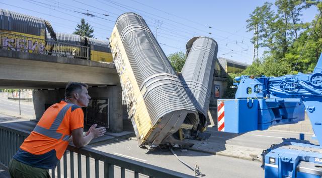 20 June 2026, Bavaria, Munich: A man looks at the two cars of a freight train that had fallen about five meters off a bridge during the night. According to police, two freight trains had previously collided while shunting on the railroad bridge in the Milbertshofen district of Munich. Photo: Stefan Puchner/dpa