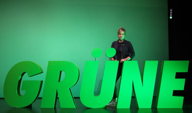 20 June 2026, North Rhine-Westphalia, Troisdorf: German Minister of Economic Affairs, Industry, Climate Protection, and Energy Deputy Minister-President of the State of North Rhine-Westphalia Mona Neubaur stands behind the word "Grüne" (Greens), written in large letters on the stage, during the party's state convention. Photo: Christoph Reichwein/dpa