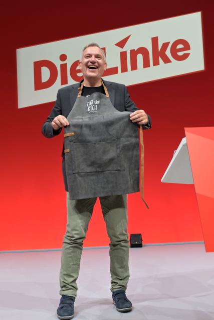 20 June 2026, Brandenburg, Potsdam: Jan van Aken, former party chair of Die Linke (The Left), receives a barbecue apron emblazoned with the words "Tax the rich" as a farewell gift upon stepping down from his position at Die Linke's federal party convention at the Metropolis Halle in Potsdam. Photo: Michael Bahlo/dpa