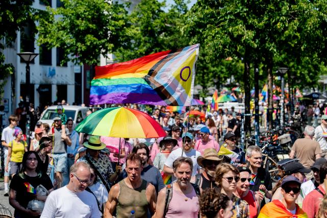 20 June 2026, Lower Saxony, Oldenburg: People march through downtown carrying flags and umbrellas during the Christopher Street Day (CSD) parade. Christopher Street Day is a demonstration and celebration of the LGBTQ+ rights. Photo: Hauke-Christian Dittrich/dpa
