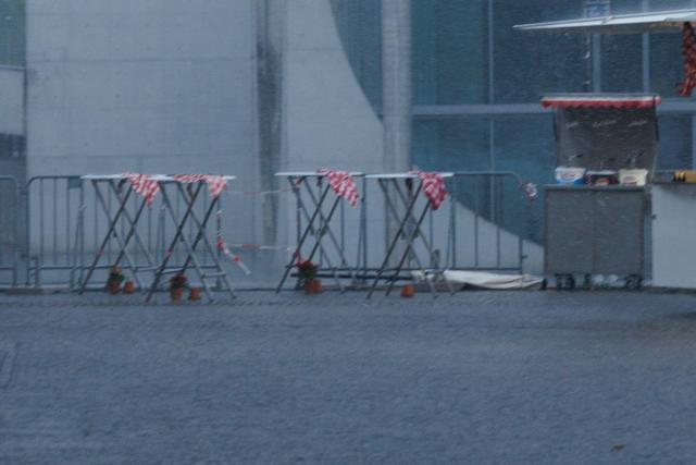 21 June 2026, Berlin: Tablecloths are blown off bar tables during a heavy downpour at a food stand set up across the grounds of a Veterans Day celebration in front of the Reichstag building. Photo: Carsten Koall/dpa