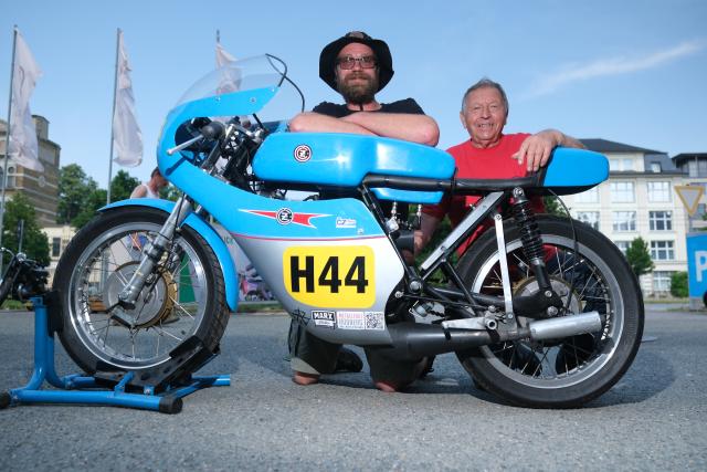 21 June 2026, Saxony, Chemnitz: Maximilian Wienhold (L) and Uwe Schneider crouch next to a 1963 CZ 250 racing motorcycle as fans of Czech motorcycles gather in Chemnitz for the Jawa meet. Photo: Sebastian Willnow/dpa