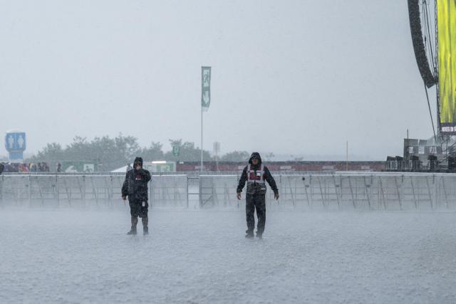 21 June 2026, Baden-Wuerttemberg, Neuhausen ob Eck: Two Southside Festival staff members are standing on the festival grounds during a rain shower. Admission for festivalgoers was temporarily suspended due to the weather. Photo: Silas Stein/dpa