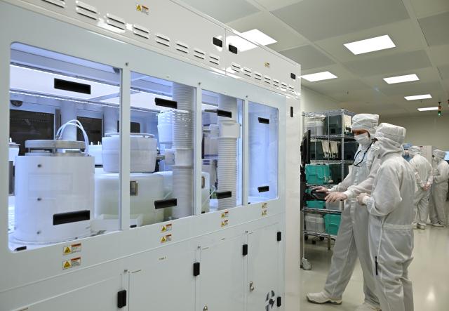 23 June 2026, Thuringia, Erfurt: Employees work in the clean-room of the Erfurt-based chip manufacturer X-FAB. The X-FAB Group, which has factories in Erfurt and Dresden as well as in France, Malaysia, and the US, employs more than 4,000 people, according to the company. In Erfurt, where the company has its roots, there are currently more than 800 employees. Photo: Martin Schutt/dpa