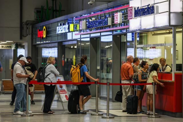 23 June 2026, North Rhine-Westphalia, Duisburg: Passengers are lining up at the DB information desk at the Duisburg train station. Germany's Deutsche Bahn temporarily suspended its train services nationwide on Tuesday evening following a disruption to its communications system, the state-owned rail operator said. Photo: Christoph Reichwein/dpa