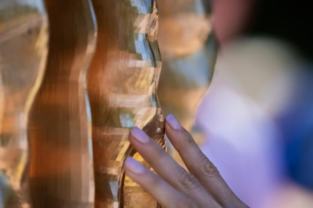 24 June 2026, Berlin: A person touches the memorial to the Jehovah's Witnesses persecuted and murdered under the Nazi regime, located in Berlin's Tiergarten park. Photo: Christoph Soeder/dpa