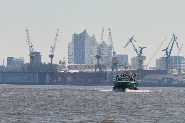 25 June 2026, Hamburg: A passenger ferry sails through the harbour with the Elbphilharmonie and port cranes visible in the background. Photo: Georg Wendt/dpa