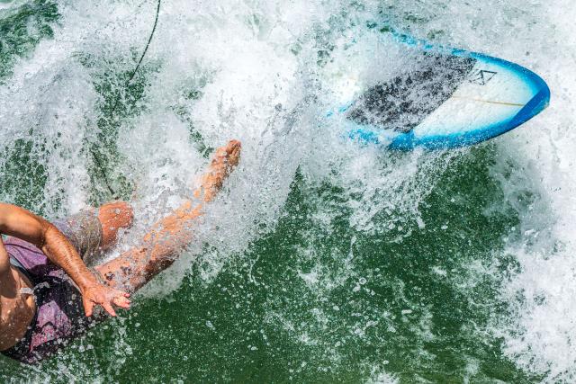 25 June 2026, Bavaria, Munich: A surfer plunges into the cool waters of the Eisbach Wave after riding its standing wave in the English Garden during the height of summer. A popular hotspot for surfers and tourists alike, it attracts visitors year-round, regardless of season or time of day. Photo: Peter Kneffel/dpa