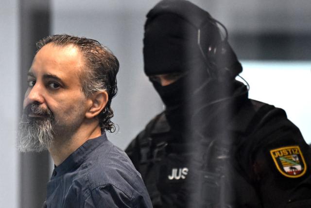 26 June 2026, Saxony-Anhalt, Magdeburg: A court officer leads the defendant, Taleb al-Abdulmohsen, into the courtroom. On December 20, 2024, the defendant drove a rental car through the crowded Christmas market. As a result of the attack, which lasted just over a minute, five women and a nine-year-old boy were killed, and hundreds of people were injured. Photo: Hendrik Schmidt/dpa