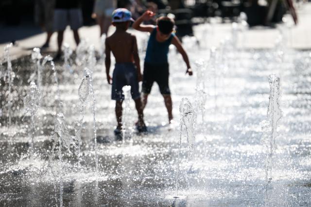 26 June 2026, North Rhine-Westphalia, Duisburg: Children play in the water jets of a walk-through fountain in the city center amid midsummer temperatures. Photo: Christoph Reichwein/dpa