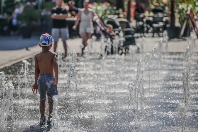 26 June 2026, North Rhine-Westphalia, Duisburg: A child plays in the water jets of a walk-through fountain in the city center amid the heat of summer. Photo: Christoph Reichwein/dpa
