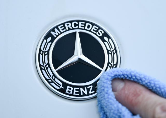 FILED - 17 February 2025, Baden-Württemberg, Stuttgart: A hand is cleaning the logo on a Mercedes-Benz vehicle. Photo: Bernd Weißbrod/dpa