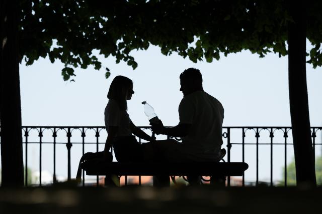 26 June 2026, Saxony, Dresden: People sit on a bench in the shade of a tree during a heat wave in Dresden. Photo: Sebastian Kahnert/dpa